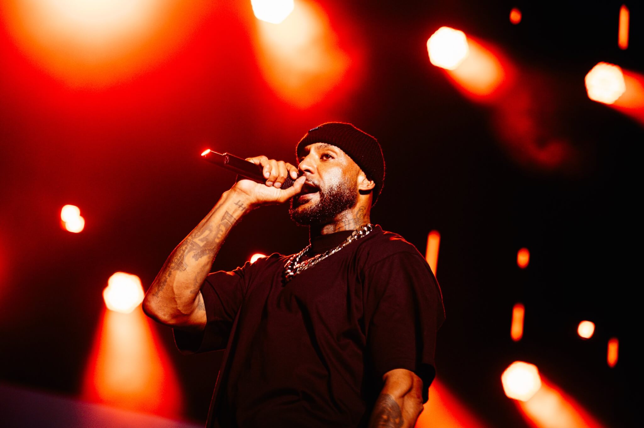 French rapper, Booba, holding microphone with red lights on stage